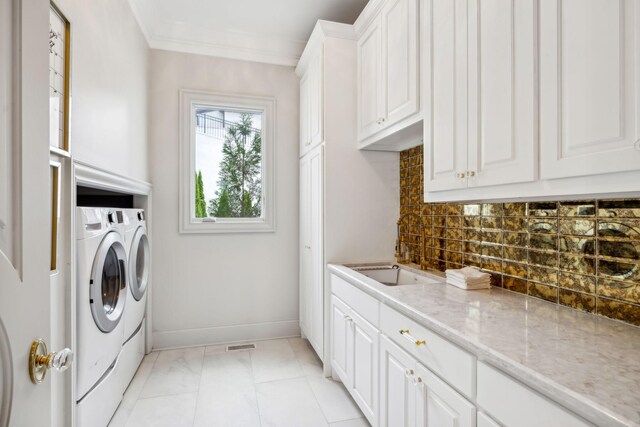 laundry area with crown molding, cabinets, and washing machine and clothes dryer