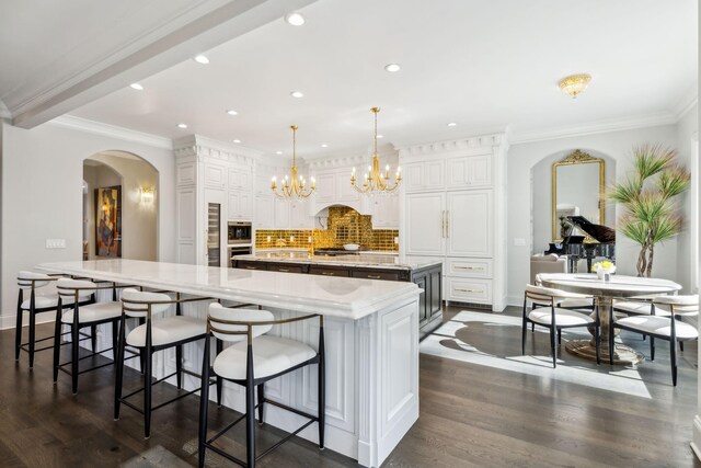 kitchen featuring a kitchen breakfast bar, a spacious island, an inviting chandelier, and light stone countertops