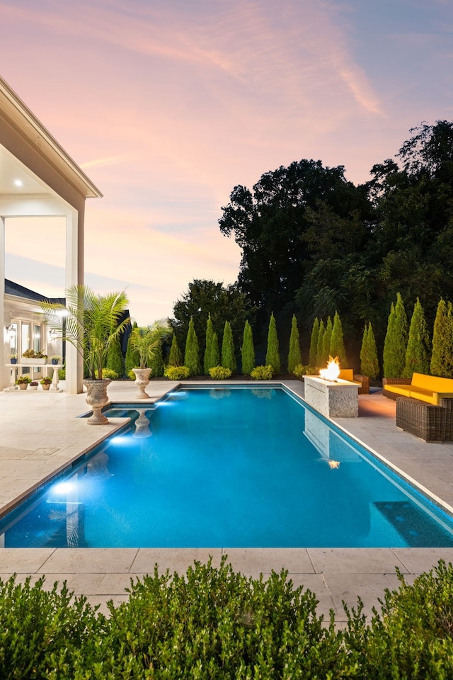 pool at dusk featuring a patio area