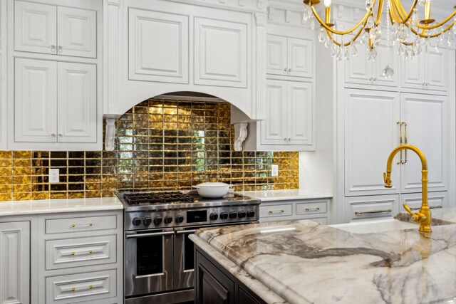 kitchen featuring decorative light fixtures, double oven range, decorative backsplash, a chandelier, and white cabinets