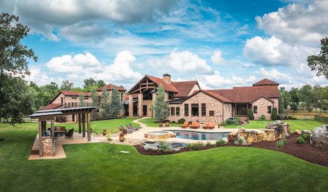 rear view of house with a swimming pool with hot tub, a yard, and a patio