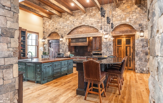 wine area with beam ceiling, light hardwood / wood-style floors, and sink