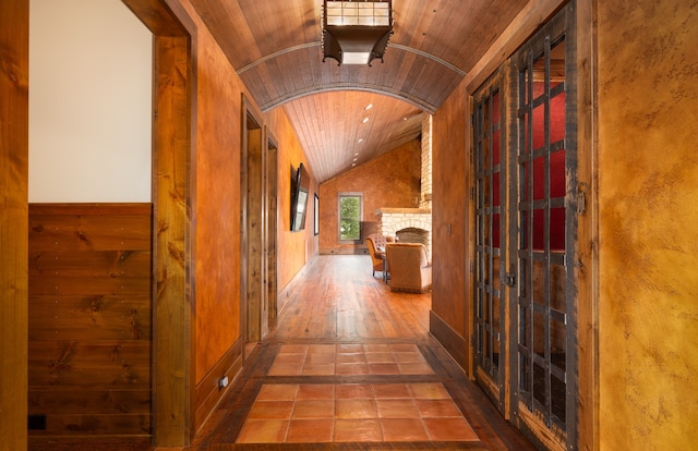 hall with wood ceiling, lofted ceiling, hardwood / wood-style flooring, and wooden walls