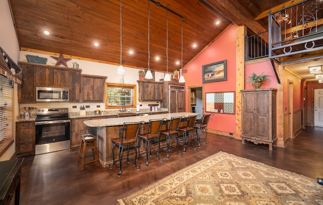 kitchen with a kitchen island, a breakfast bar area, decorative light fixtures, stainless steel appliances, and high vaulted ceiling