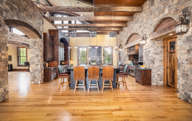 dining area featuring light wood-type flooring, beamed ceiling, and high vaulted ceiling