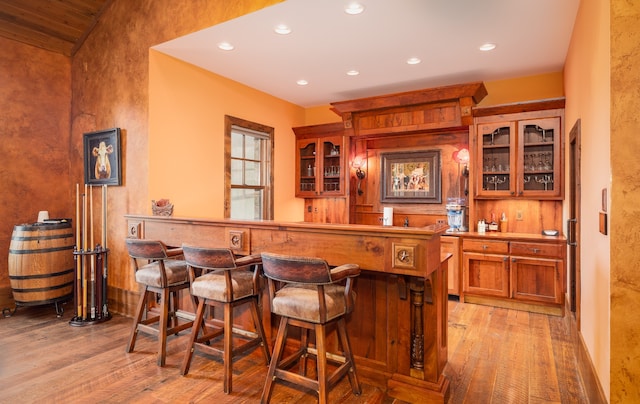 bar featuring lofted ceiling and light hardwood / wood-style flooring