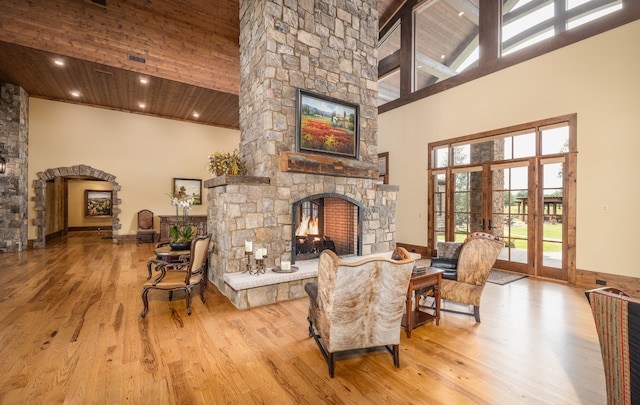 living room featuring a stone fireplace, french doors, light hardwood / wood-style floors, wood ceiling, and high vaulted ceiling