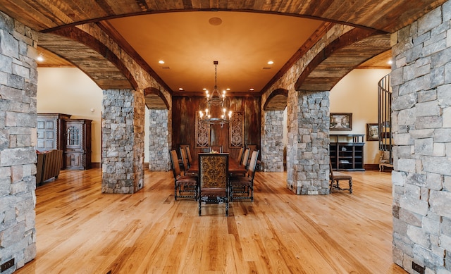 unfurnished dining area featuring ornamental molding, light hardwood / wood-style flooring, a notable chandelier, and decorative columns