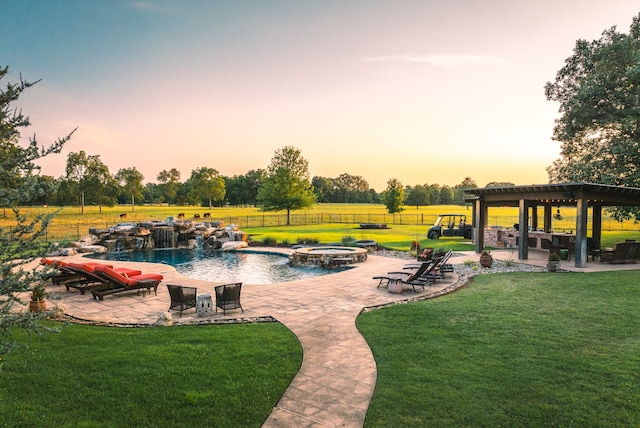 pool at dusk featuring a pergola, a patio area, and a lawn