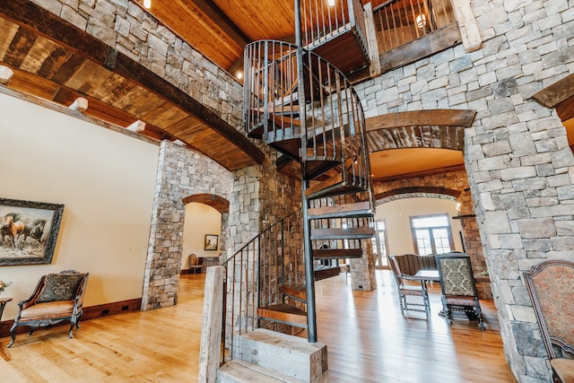 stairway featuring wooden ceiling, beamed ceiling, hardwood / wood-style flooring, and a high ceiling