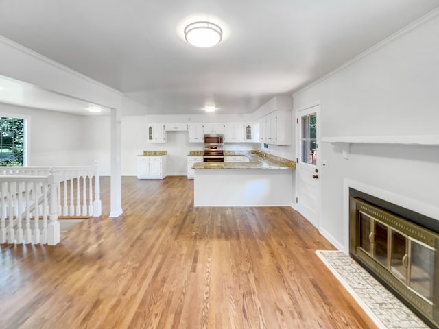 kitchen with kitchen peninsula, hardwood / wood-style flooring, stainless steel appliances, and white cabinets