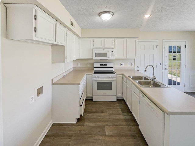 kitchen with dark wood-type flooring, white appliances, sink, and a textured ceiling