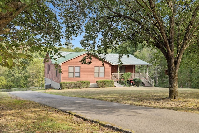 view of front of house with cooling unit, covered porch, and a front yard