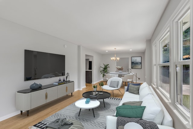 living room with a notable chandelier, light hardwood / wood-style floors, and a wealth of natural light