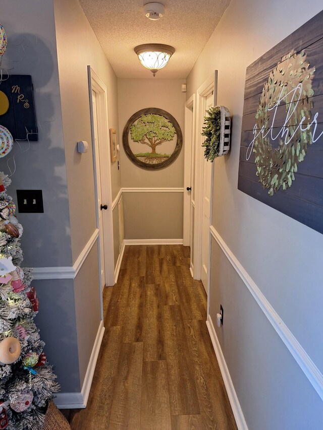 hall featuring dark wood-type flooring and a textured ceiling