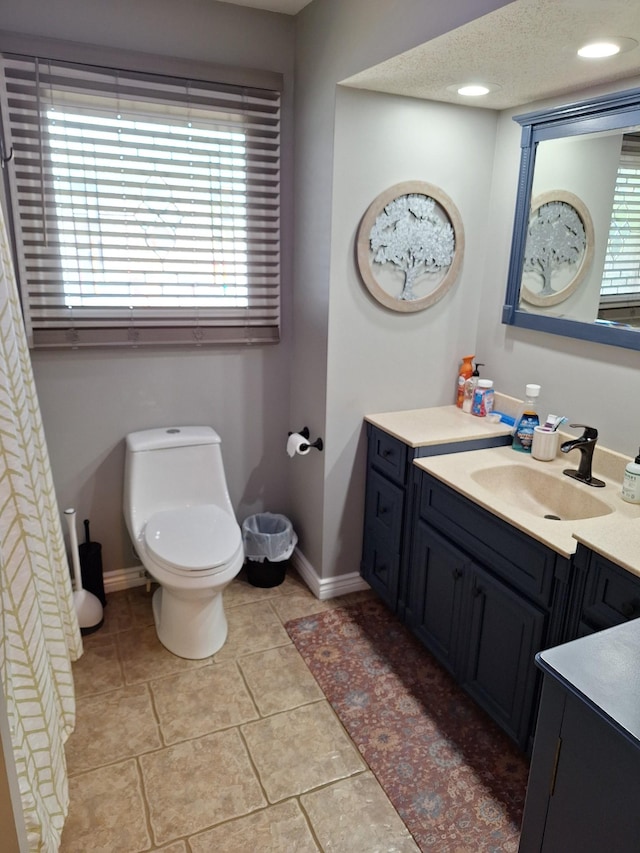 bathroom with vanity, toilet, baseboards, and plenty of natural light