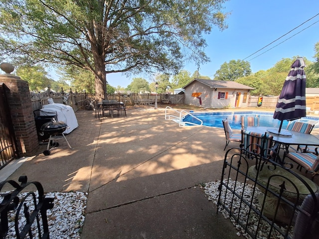 view of pool with outdoor dining space, an outdoor structure, a fenced backyard, and a patio area