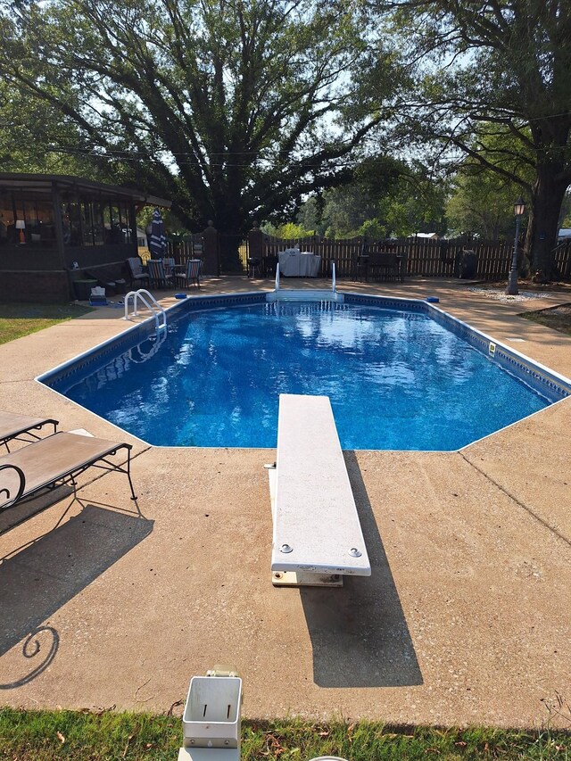 view of pool featuring a sunroom, a diving board, and a patio