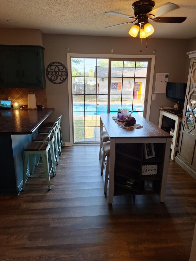 dining area featuring dark hardwood / wood-style flooring, plenty of natural light, ceiling fan, and a textured ceiling