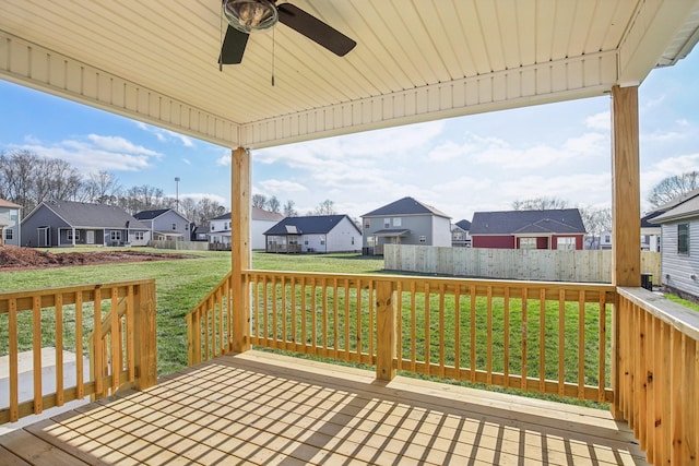 wooden terrace featuring ceiling fan and a yard