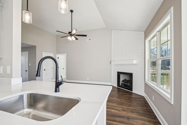 kitchen with pendant lighting, lofted ceiling, dark wood-type flooring, sink, and ceiling fan