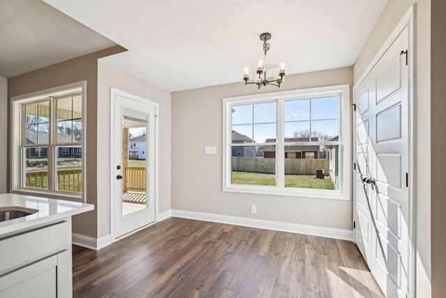 unfurnished dining area with dark wood-type flooring and a notable chandelier