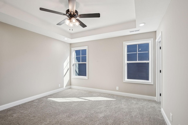 unfurnished room with light carpet, ceiling fan, and a raised ceiling