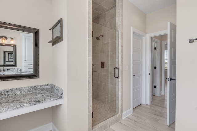 bathroom featuring hardwood / wood-style flooring, vanity, and a shower with shower door