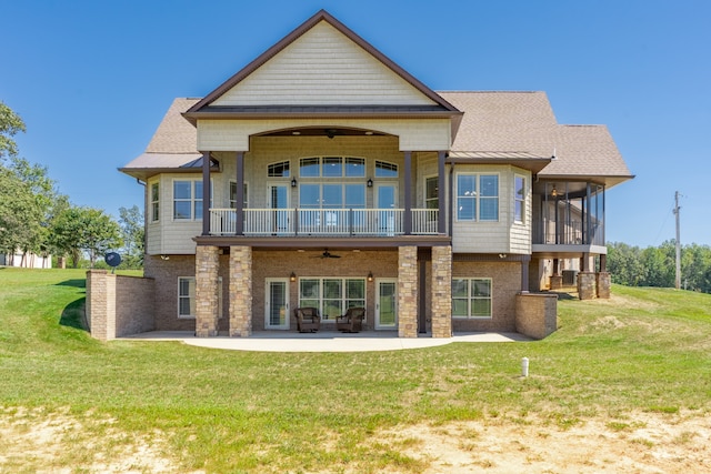 back of house with ceiling fan, a balcony, a lawn, and a patio area