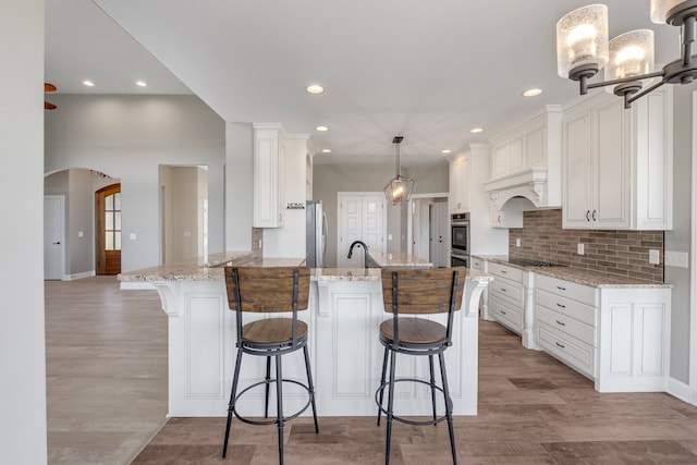 kitchen with light stone counters, white cabinets, hanging light fixtures, and kitchen peninsula