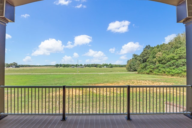 wooden terrace with a rural view and a lawn