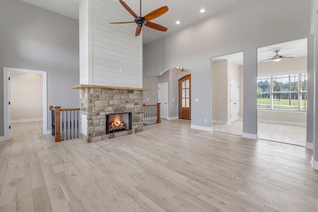 unfurnished living room with a fireplace, high vaulted ceiling, and light wood-type flooring