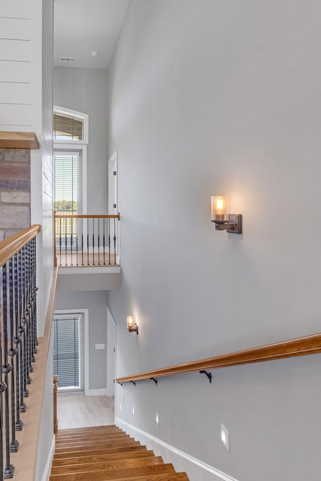 stairway with a towering ceiling and hardwood / wood-style floors