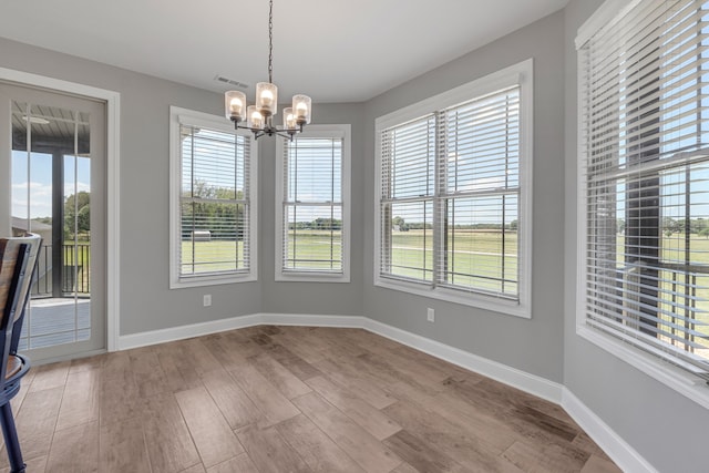 unfurnished dining area featuring hardwood / wood-style flooring, plenty of natural light, and an inviting chandelier