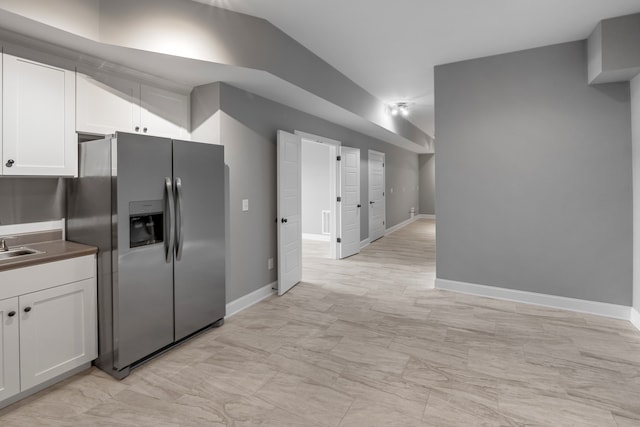 kitchen with white cabinetry, sink, and stainless steel refrigerator with ice dispenser