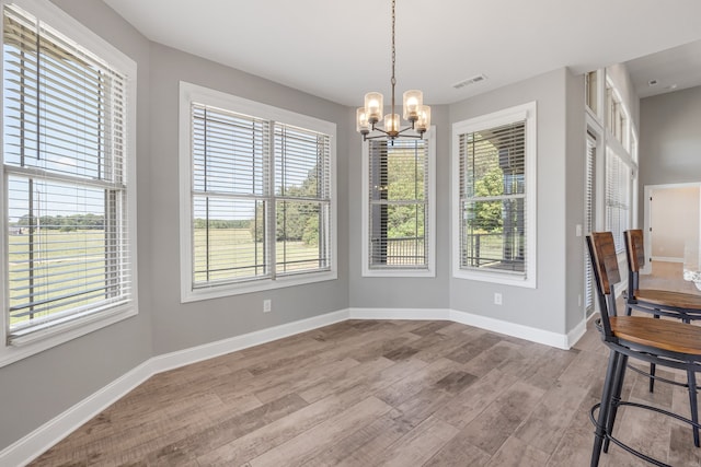 dining room with a notable chandelier, light wood-type flooring, and a healthy amount of sunlight