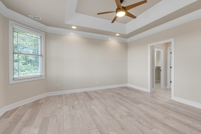 spare room with ceiling fan, light wood-type flooring, crown molding, and a tray ceiling