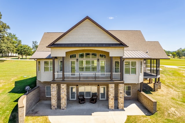 rear view of property featuring a lawn, a patio area, and a balcony