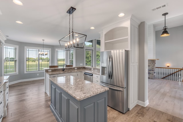 kitchen with stainless steel appliances, light wood-type flooring, decorative light fixtures, and a wealth of natural light