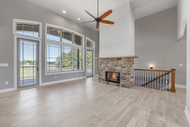 unfurnished living room with a high ceiling, a healthy amount of sunlight, a fireplace, and light hardwood / wood-style floors