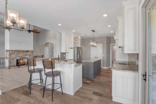 kitchen with white cabinets, gray cabinetry, light hardwood / wood-style floors, kitchen peninsula, and pendant lighting