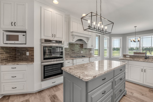 kitchen featuring pendant lighting, sink, a kitchen island, gray cabinetry, and double oven