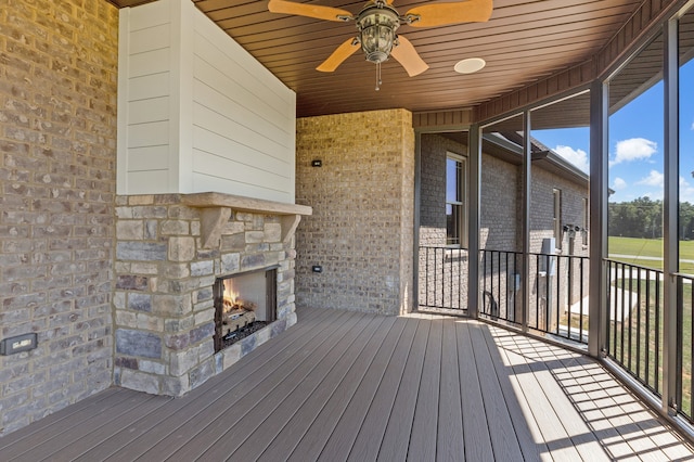 deck featuring an outdoor stone fireplace and ceiling fan