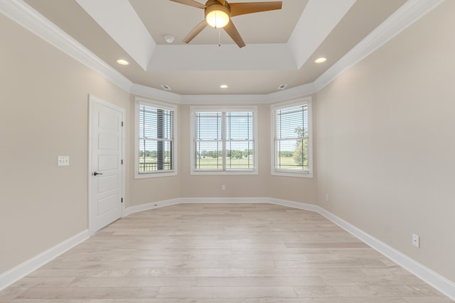 spare room featuring light wood-type flooring, crown molding, and a raised ceiling