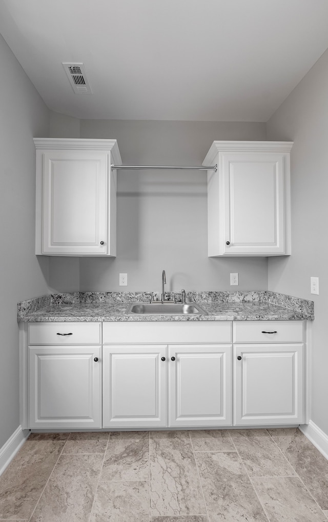 kitchen with white cabinets, sink, and light stone counters