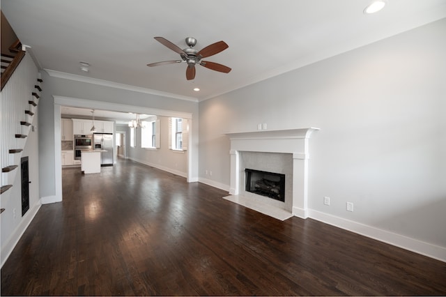 unfurnished living room with dark wood-type flooring, ornamental molding, ceiling fan with notable chandelier, and a fireplace