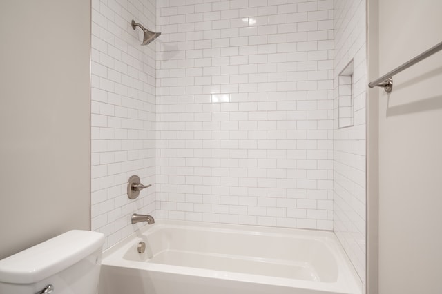 bathroom featuring tiled shower / bath combo and toilet