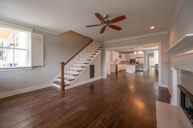 unfurnished living room featuring ceiling fan with notable chandelier, a wealth of natural light, a fireplace, and dark hardwood / wood-style flooring