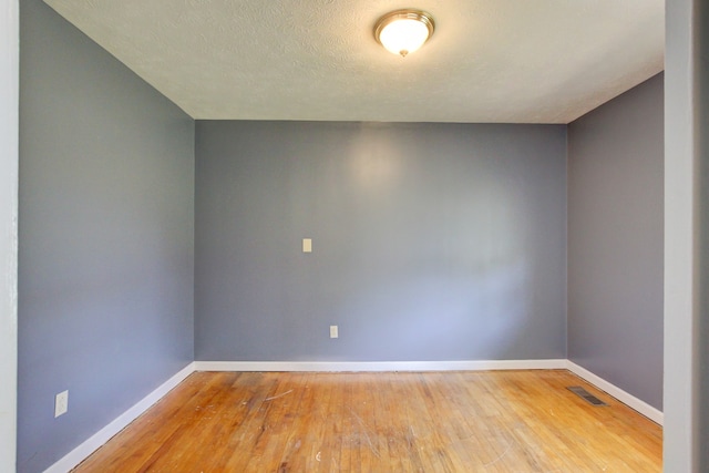 unfurnished room featuring a textured ceiling and light hardwood / wood-style floors