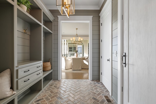 mudroom with crown molding and a chandelier